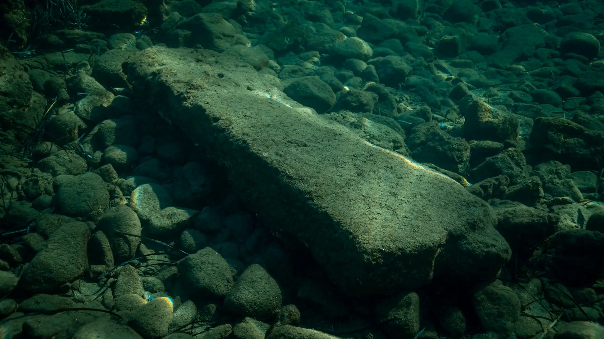Bloque de piedra caído sobre un fondo de rocas cubiertas de algas