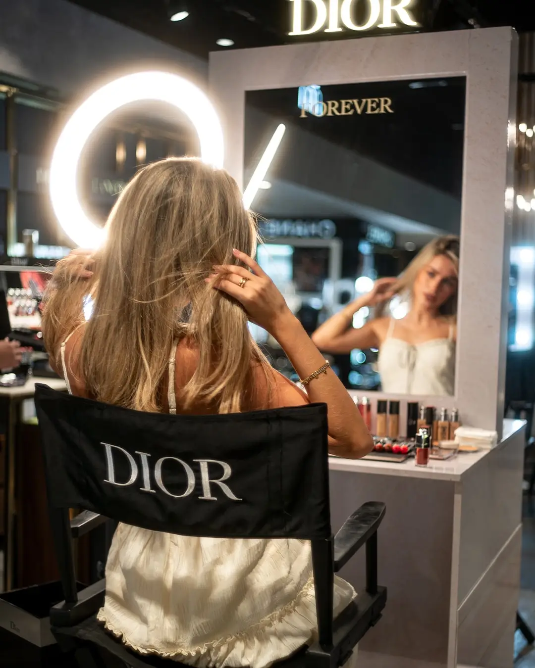 Modelo de espaldas en una silla de maquillaje frente al espejo iluminado